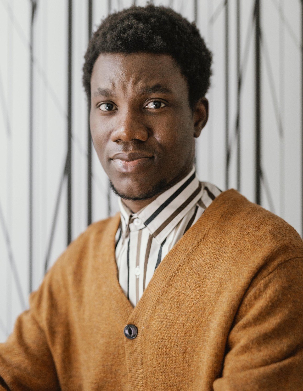 Homme en veste et chapeau sur fond sombre.